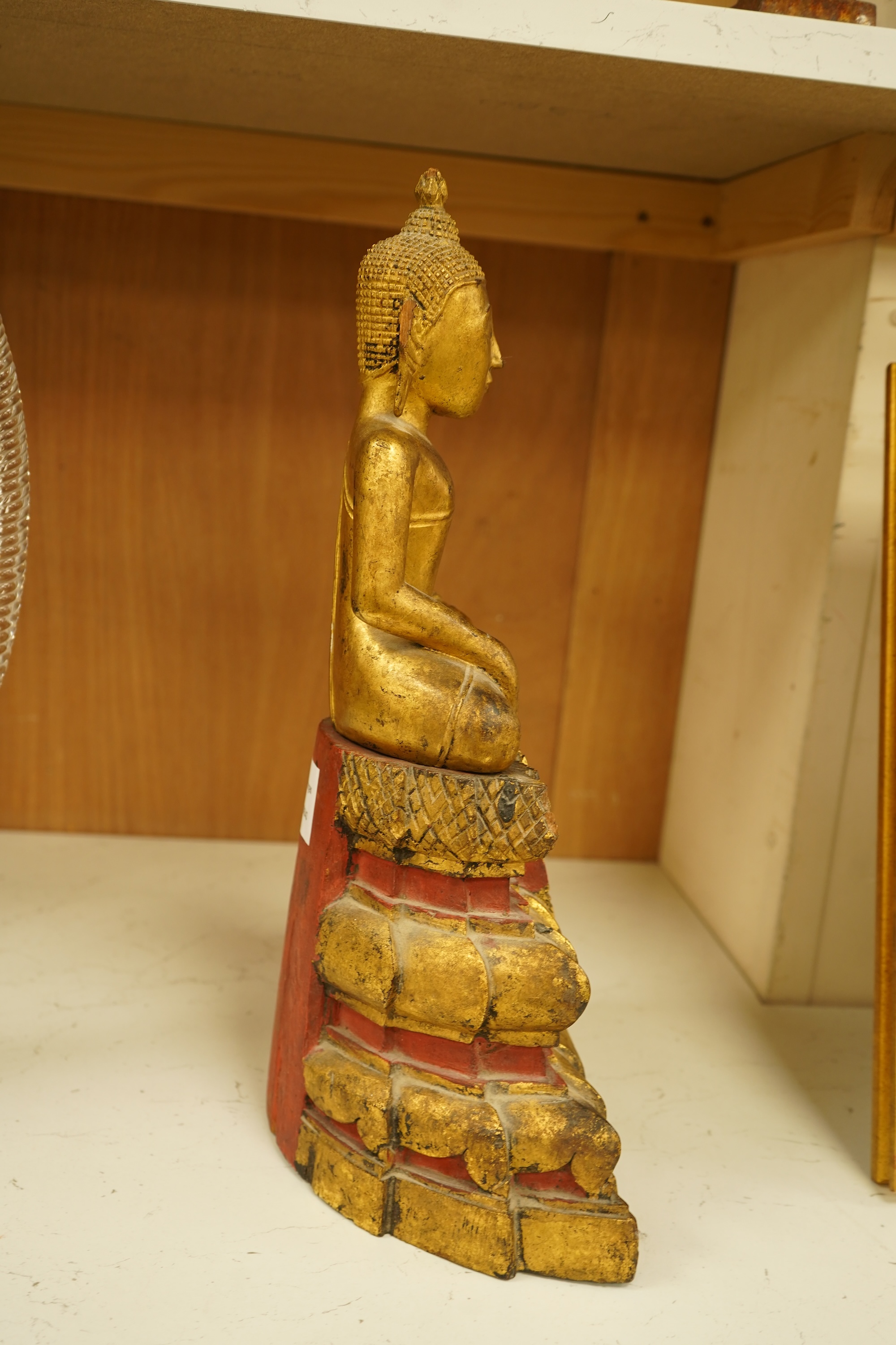 A 19th century Burmese giltwood figure of seated Buddha, 40cm high